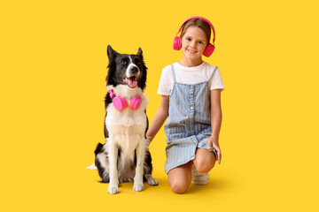 Cute little girl and Border Collie dog with headphones on yellow background