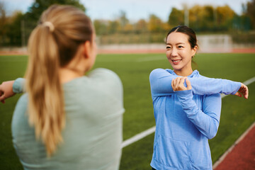 Women friends stretching enjoying outdoor fitness workout