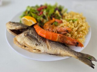 Fried fish with side dish on a plate. Fish day. Fish with lemon.