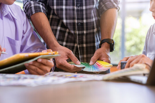 Team graphic designer checking print quality of media graphics proof print and color guides in printing industry. Selected focus