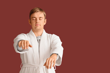 Male sleepwalker in pajamas on burgundy background