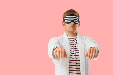 Male sleepwalker in pajamas on pink background