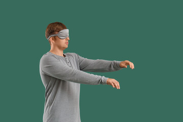 Male sleepwalker in pajamas on green background