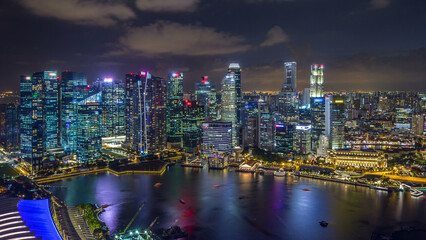 Obraz premium Aerial view of Singapore business district skyscrapers at evening with water reflections day to night timelapse