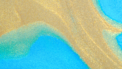 Abstract macro photo showing shimmering golden powder flowing over bright turquoise blue surface. Glitter texture resembling sea waves or sand art pattern.