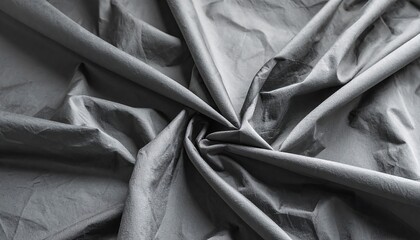 An overhead view showcases draped, matte fabric in gray tones, formed into a spiraling pattern from the center, creating folds and shadows