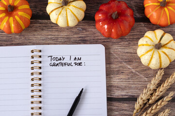Today I am grateful for, handwritten text in notebook with pumpkin fruit of wooden background. Top view. Thanksgiving day concept.