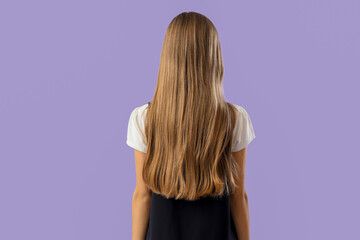 Obraz premium Teenage schoolgirl on lilac background, back view