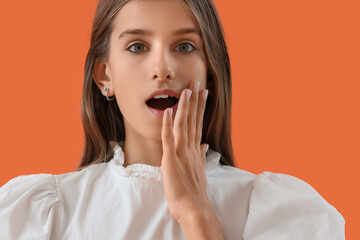 Fototapeta premium Shocked teenage girl on orange background, closeup