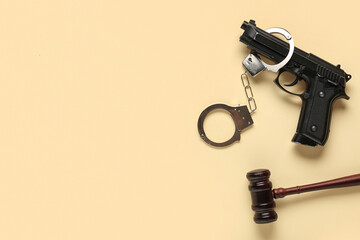 Gun with handcuffs and judge's gavel on beige background. Crime concept