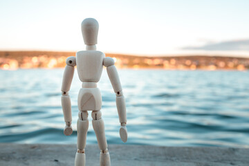 A wooden figure stands on a beach near the water