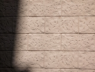 Textured beige block wall background with diagonal shadow