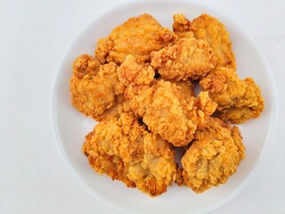 Breaded fried chicken in a white plate on a white background.