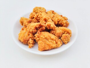Breaded fried chicken in a white plate on a white background.