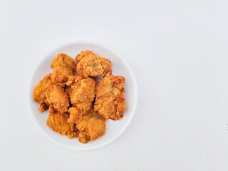 Breaded fried chicken in a white plate on a white background.