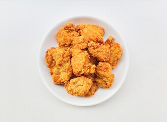 Breaded fried chicken in a white plate on a white background.