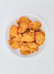 Breaded fried chicken in a white plate on a white background.