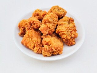 Breaded fried chicken in a white plate on a white background.