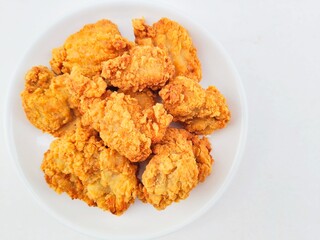Breaded fried chicken in a white plate on a white background.