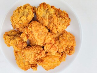 Breaded fried chicken in a white plate on a white background.