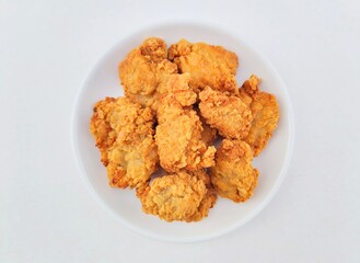 Breaded fried chicken in a white plate on a white background. Top of view. 