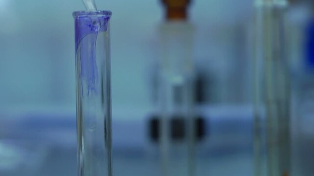 Химик наливает синюю жидкость в колбу в лаборатории