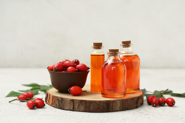 Bottles of cosmetic rose hip oil and bowl with berries on white background
