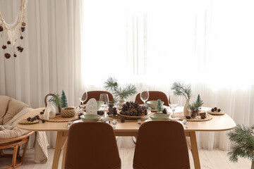 Winter table setting with pine cones and branches in room