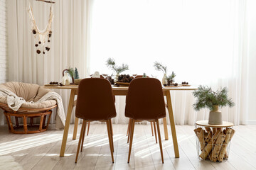 Interior of room with dining table, pine branches and armchair