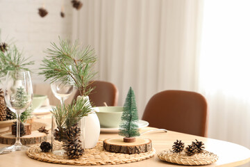 Winter table setting with pine cones and branches in room