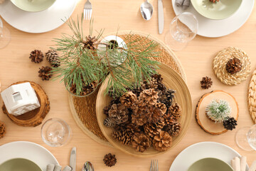 Winter table setting with pine cones and branches in room, top view