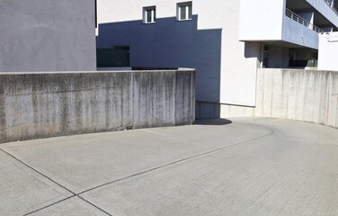 Concrete barriers siding the cement street heading to an underground parking. Buildings around it. Background for copy space.