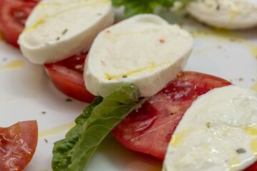 Fresh Caprese appetizer showcasing sliced tomatoes, creamy mozzarella, and green basil on a rustic dish