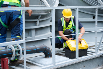 Workers opening toolbox and involved in repairing mechanical systems a cooling tower