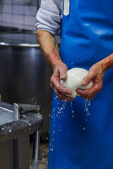Operaio di un caseificio mentre prepara la mozzarella di bufala campana a mano 