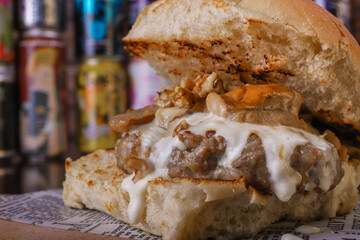 Panino da pub ripieno di funghi, hamburger di carne, provola e noci fotografato davanti a delle birre in lattina