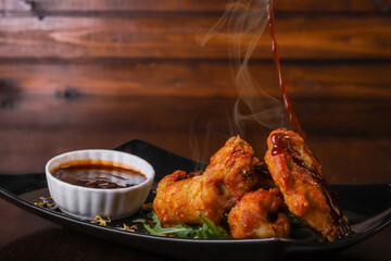 Ali di pollo fritte e fumanti servite come antipasto in un pub accompagnate da salsa barbecue