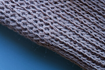 Macro of wool knit fabric in a diagonal weave; soft, warm texture with copy space on blue for text or banner. Cozy home mood, fibers and detail visible. Photo