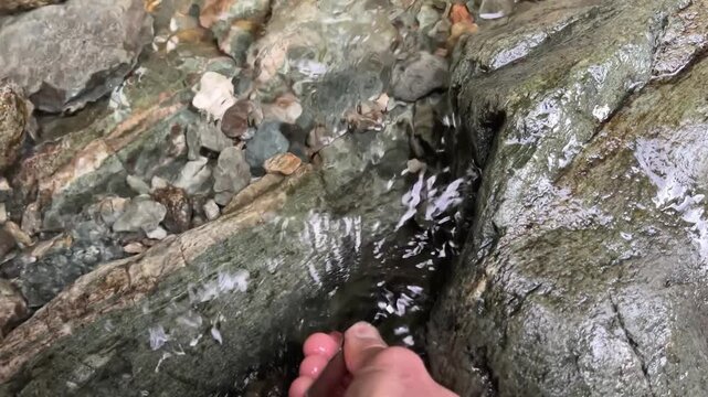 Outdoor adventures on river. Discovery of a beautiful and rare Italian nugget. Hand picking up a nugget in water. Gold panning in a mountain creek, search for gold