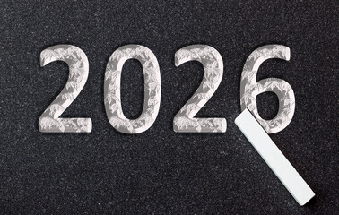 board, chalk writes the number of the new year 2026 on a black board