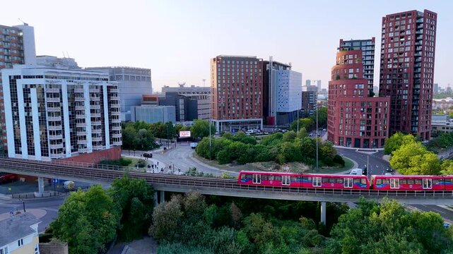 Aerial sunset view of a modern riverside city with trains, towers, and calm light. Urban motion meets golden hour harmony
