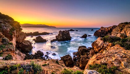 Breathtaking coastal panorama at dawn. Golden sunlight bathes craggy rock formations, gentle waves, & a serene ocean under a vibrant, multicolored sky