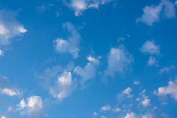 Sunny clear blue sky with white and gray clouds. Seasonal cloudscape. Nature background for environment, climate, and weather forecasting.
