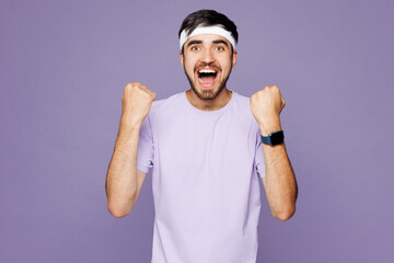Young strong fitness trainer instructor man sportsman wear headband t-shirt train in home gym show smartwatch time do winner gesture isolated on plain purple background. Workout sport fit abs concept.