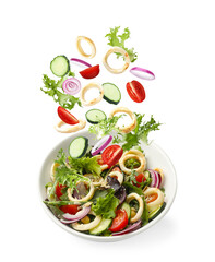 Squid rings and other ingredients falling into bowl with salad against white background