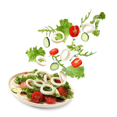 Squid rings and other ingredients falling onto plate with salad against white background