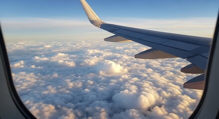 Fototapeta premium Airplane wing soars above a sea of fluffy clouds under a blue sky