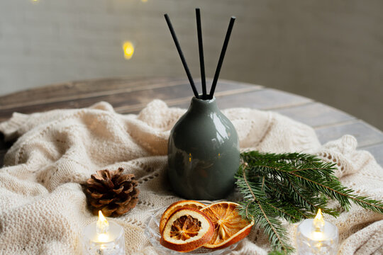 Aroma diffuser with sticks. Cozy winter home decor, aromatherapy with Christmas scent of spruce and oranges.
