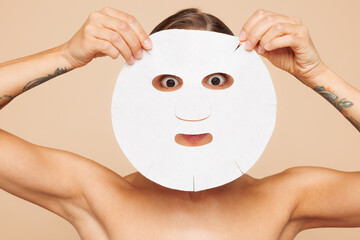Half naked topless fun young woman 20s apply tissue fabric textile face mask looking camera...