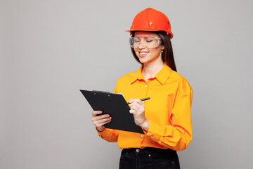 Young architect engineer designer employee white woman wear yellow clothes hardhat glasses hold clipboard sign paper account documents isolated on plain grey background. People work on build project.